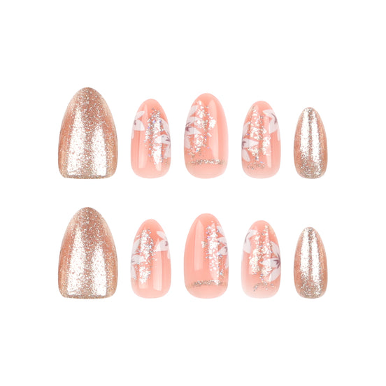 Close-up of peach press-on nails showing white floral art and rose gold glitter detail